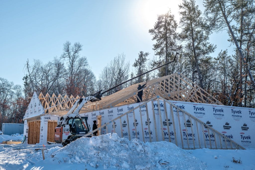 New stick-built residential home under construction during winter, with snow covering the ground.