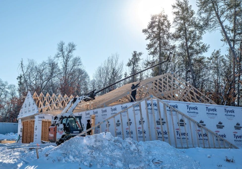 New stick-built residential home under construction during winter, with snow covering the ground.